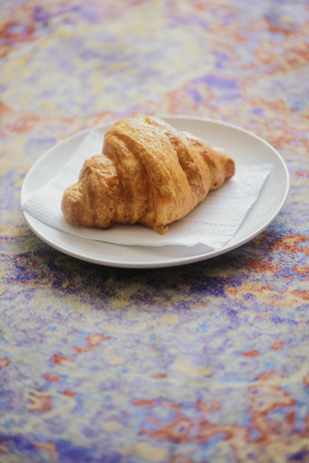 Croissant dorado de manteca sobre un plato blanco